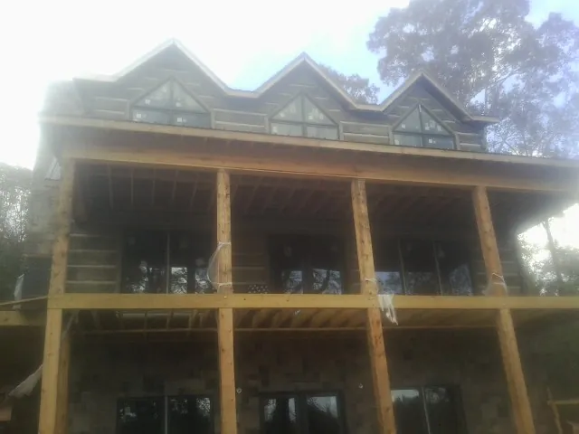 Dormers and porch framing on a large log home under construction — Roof Coating work by our crew in Kansas City