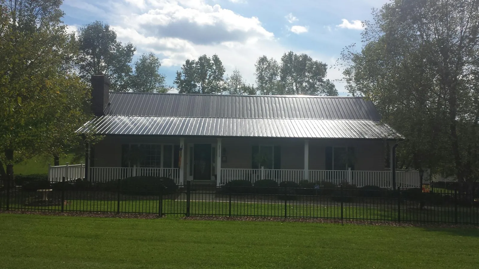 Gray metal roof on a brick ranch with a full width front porch — Gutter Guard Installation work by our crew in Kansas City