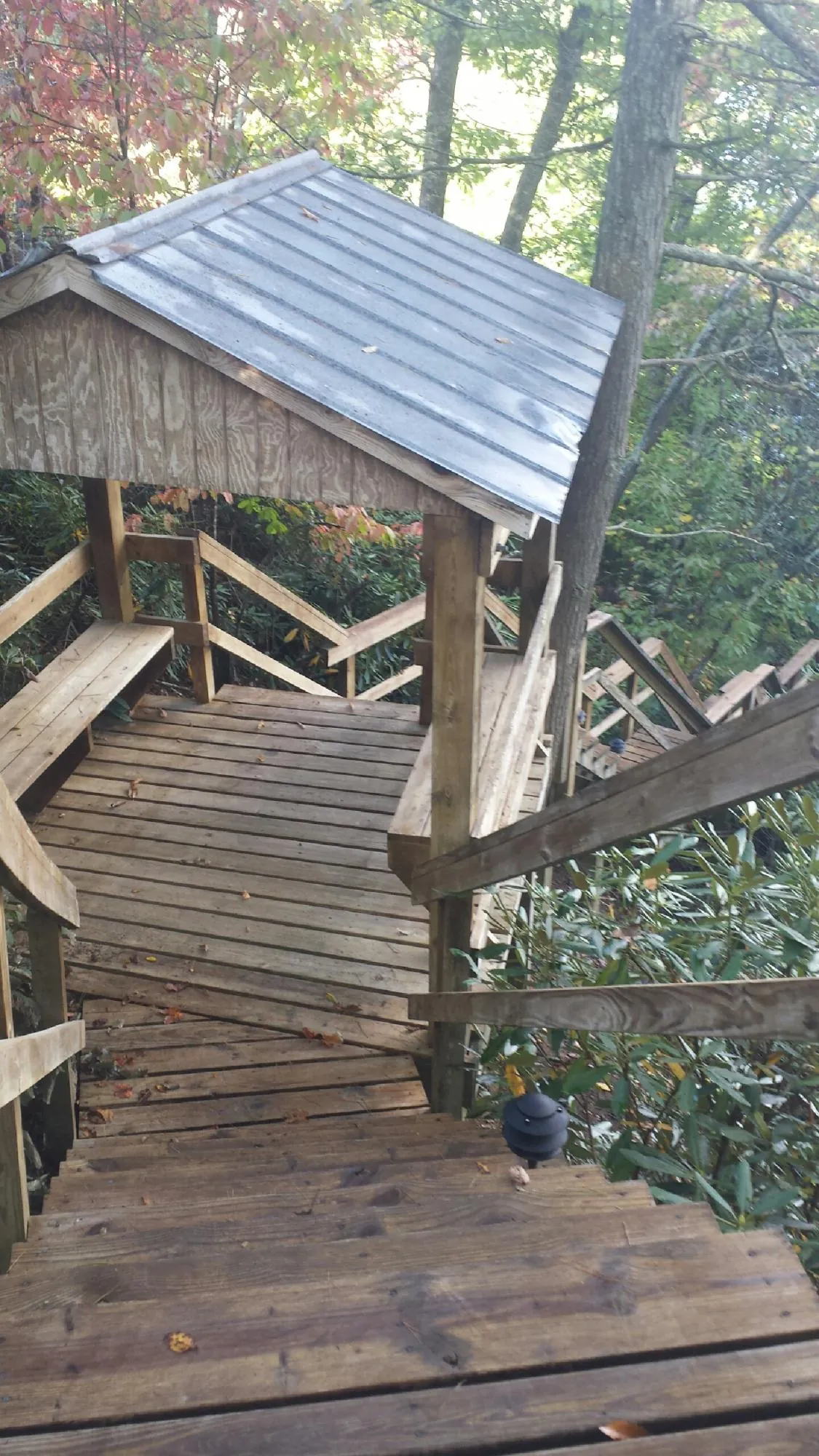 Metal roofed shelter over wooden steps on a wooded walkway — Skylight Repair & Installation work by our crew in Kansas City