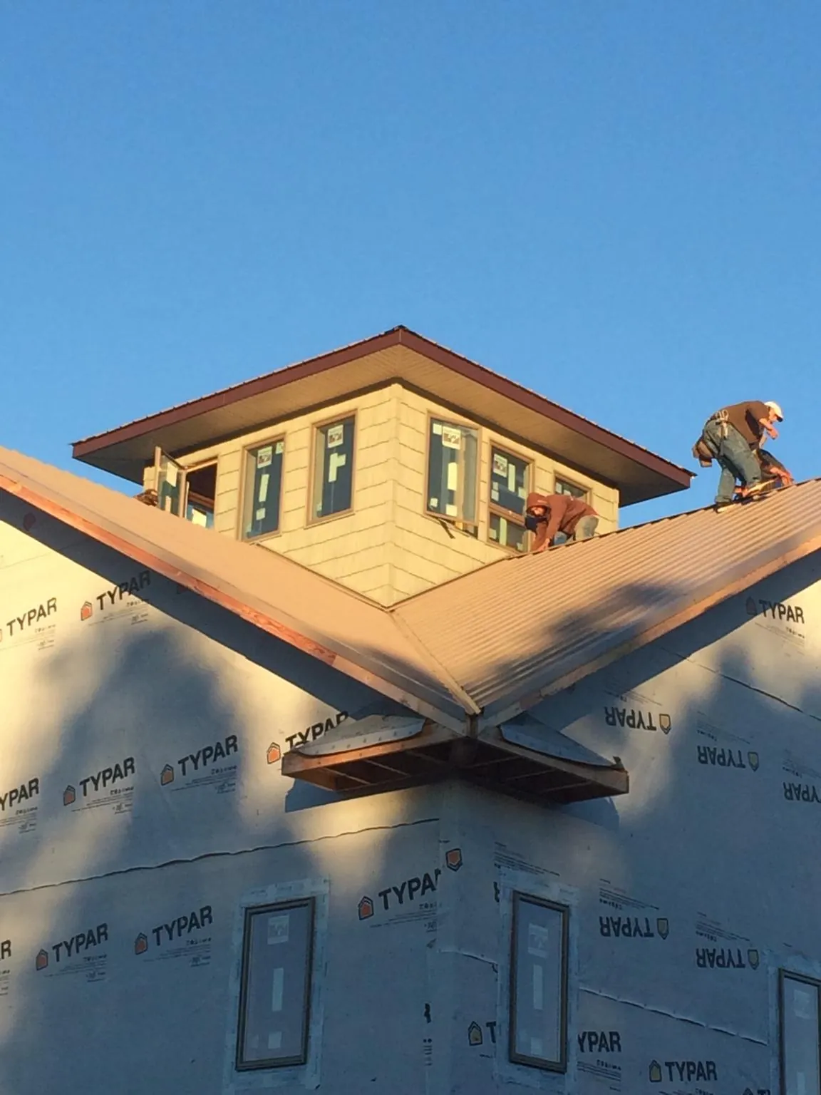 Roofers working around a rooftop cupola on a new metal roof at sunset — Roof Waterproofing in Kansas City by Roofing Brothers